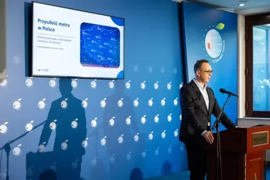 Mężczyzna w garniturze przemawia z mównicy podczas prezentacji o przyszłości metra w Polsce na forum ekonomicznym.