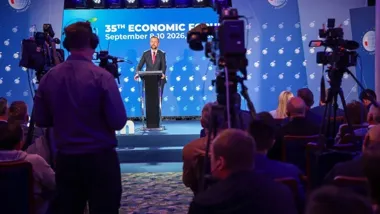 Mężczyzna w garniturze przemawia z mównicy podczas 35. Forum Ekonomicznego, transmitowanego przez telewizyjne kamery przed publicznością.