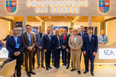 Grupa osób w strojach biznesowych pozuje do wspólnego zdjęcia na tle napisu Świętokrzyskie dla Biznesu.